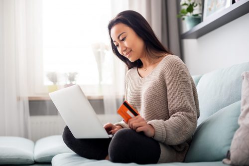 Asian girl making online payment using laptop for shopping at home